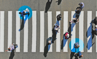 Foto vieler Menschen von oben, die über einen Zebrastreifen gehen, zwei Personen sind mit einem blauen Kreis um ihren Kopf gekennzeichnet.
